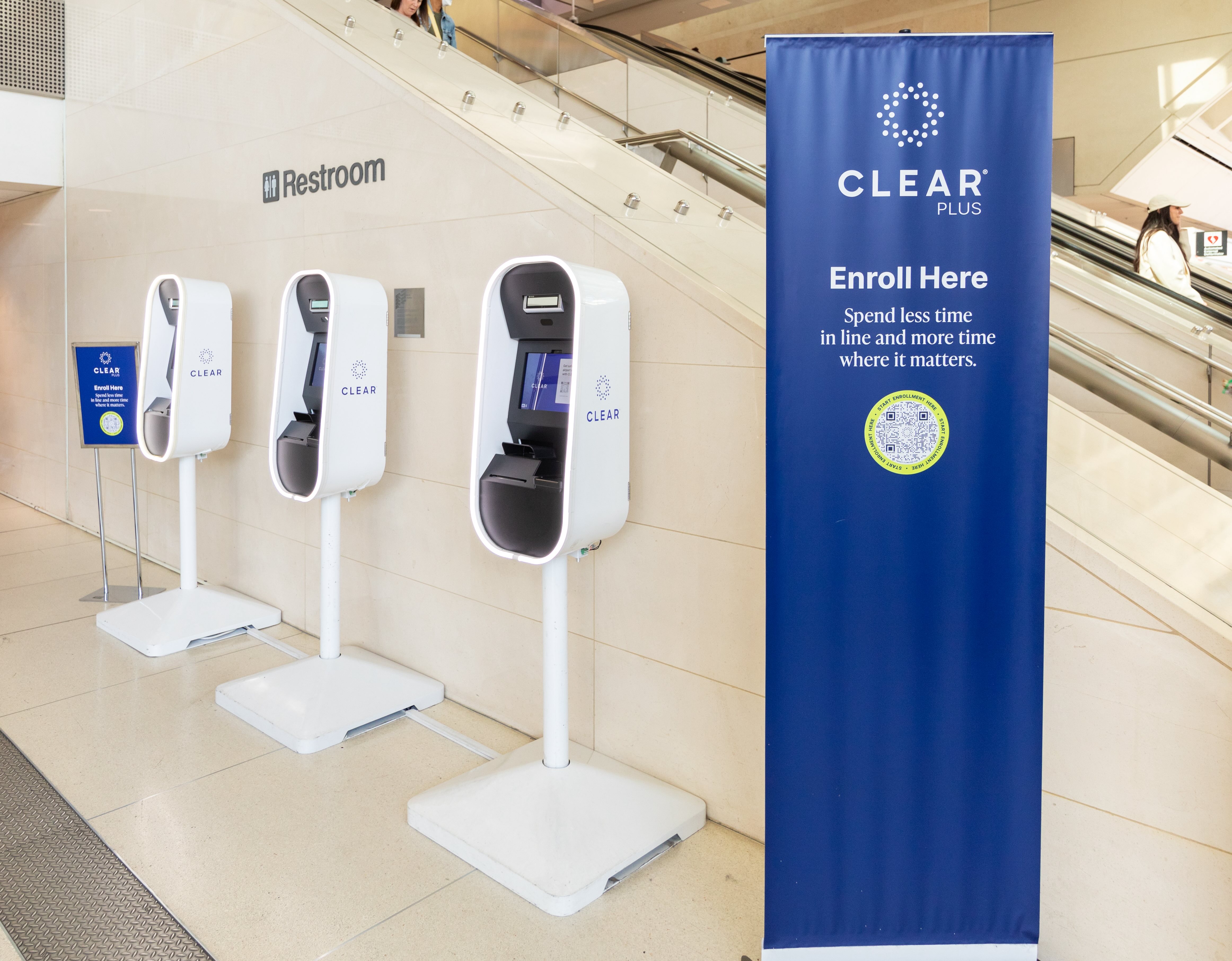 Hand sanitizer dispensers mounted on stands in a shopping area, with a blue COVID safety sign.