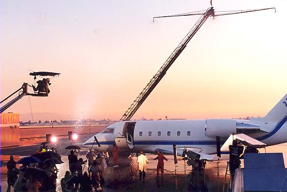 A historic photo shows film crews outside a plane on an ONT runway filming a scene at sunset.