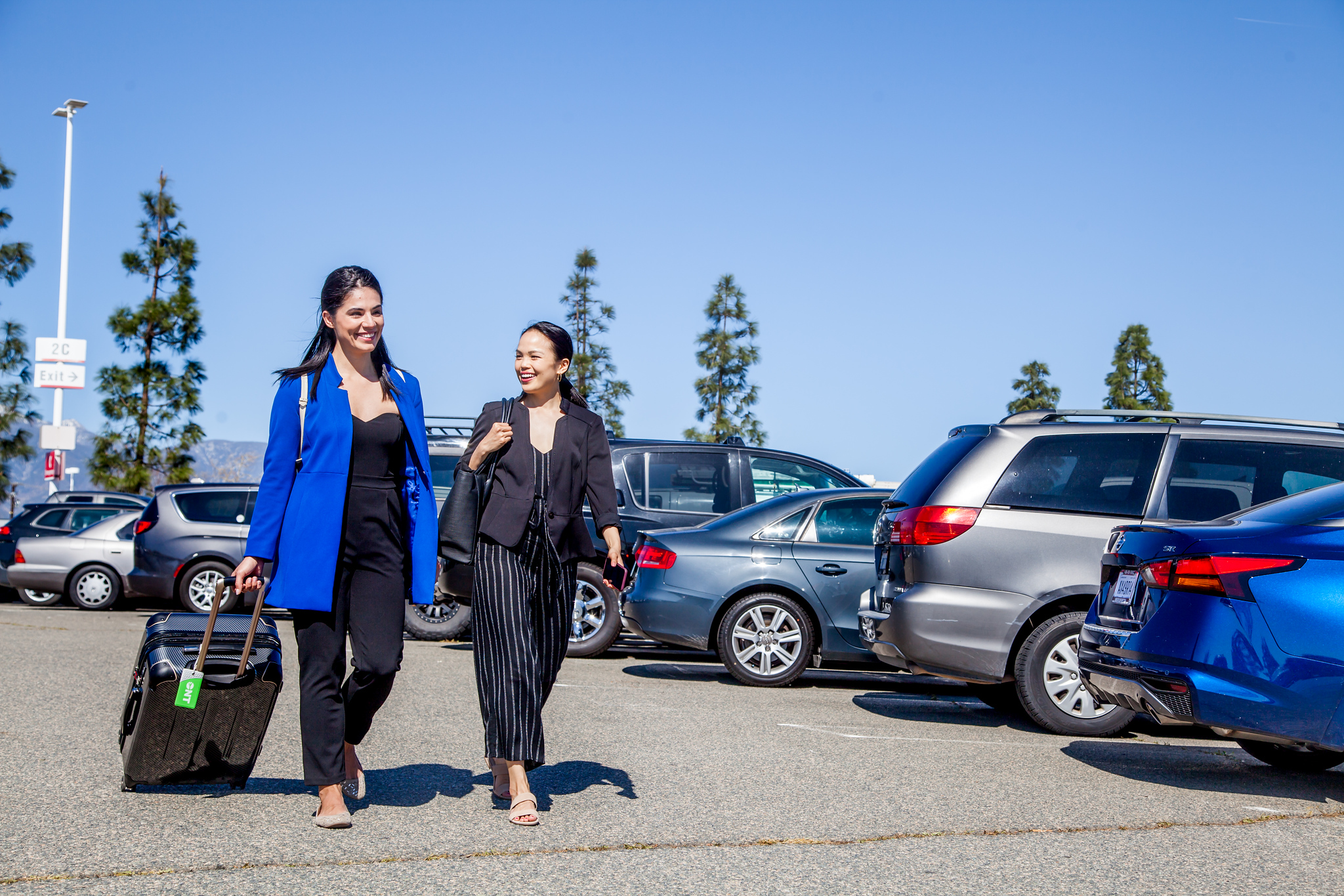 Two ONT passengers with carry-on luggage head for Terminal 2 after parking out front in Parking Lot 2.