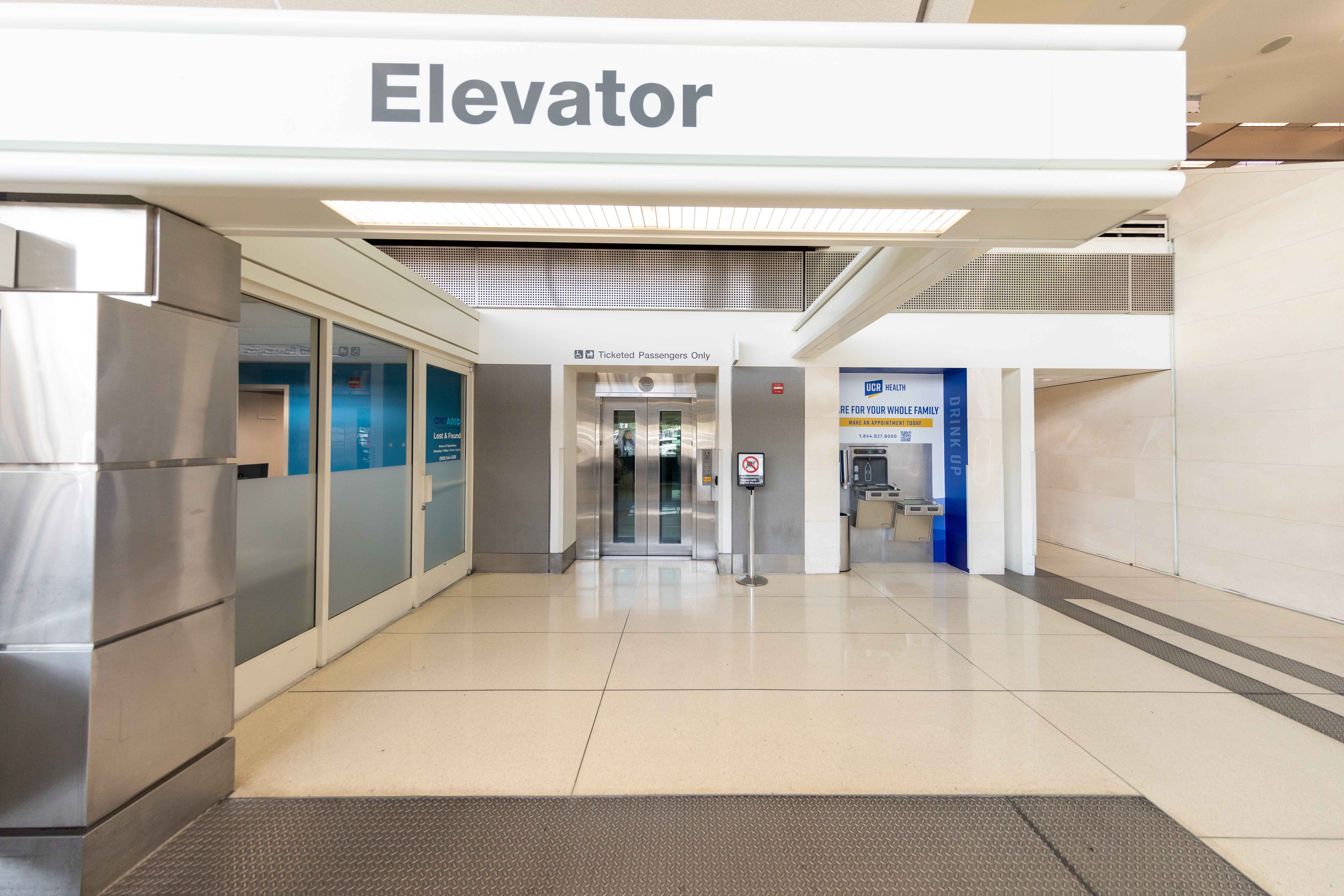 Photo shows the elevator on the ground floor of an ONT terminal with a hydration station to refill a water bottle nearby.