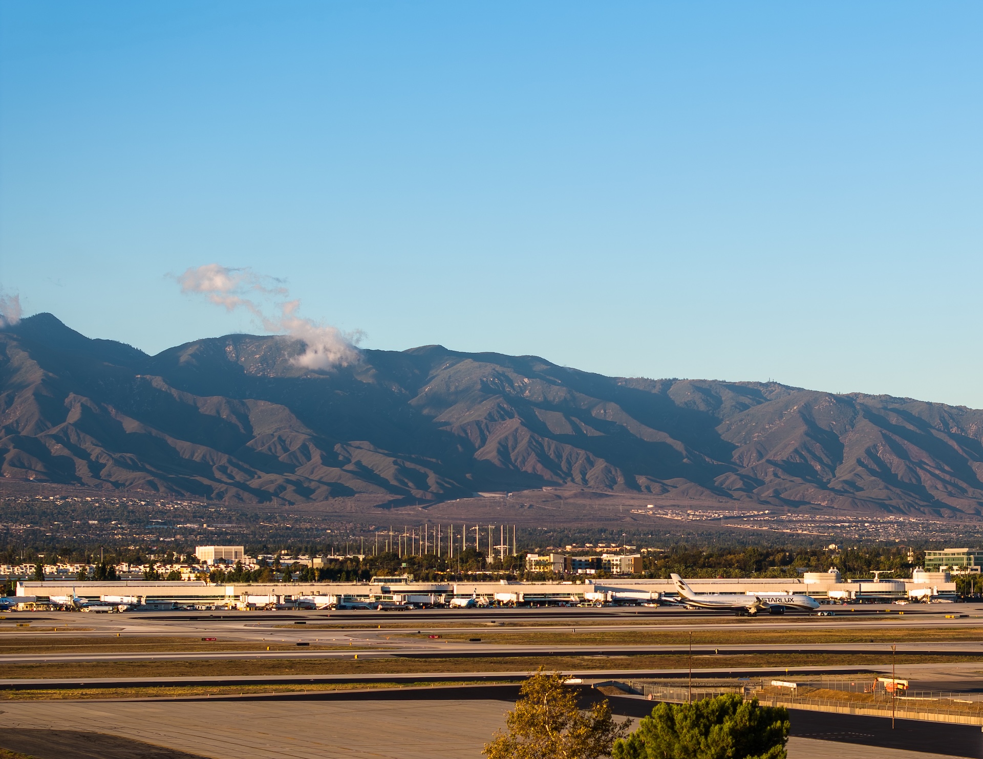 Mountain range with clear blue sky overlooking an FlyONT airport runway.
