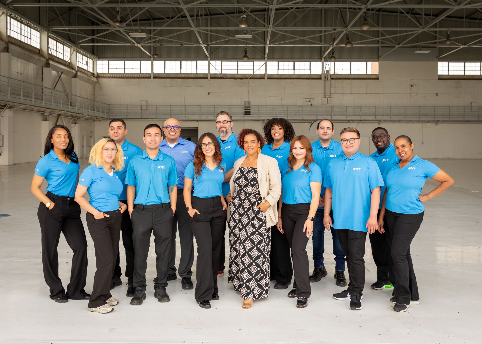 Members of ONT's Customer Experience team pose in blue ONT polo shirts inside a hangar.