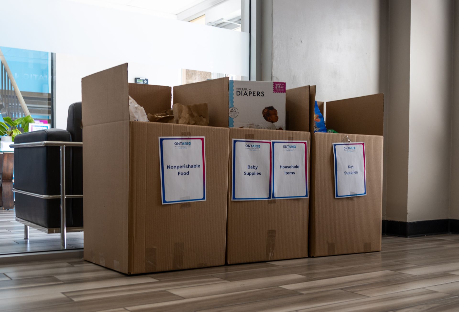 Three tall boxes are shown with signs on them asking for donations and donated items sticking out.