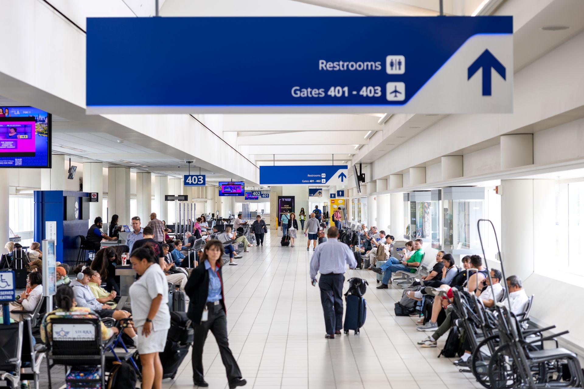 Passengers wait for flights inside Terminal 4, with some pushing luggage and some in seats on phones.