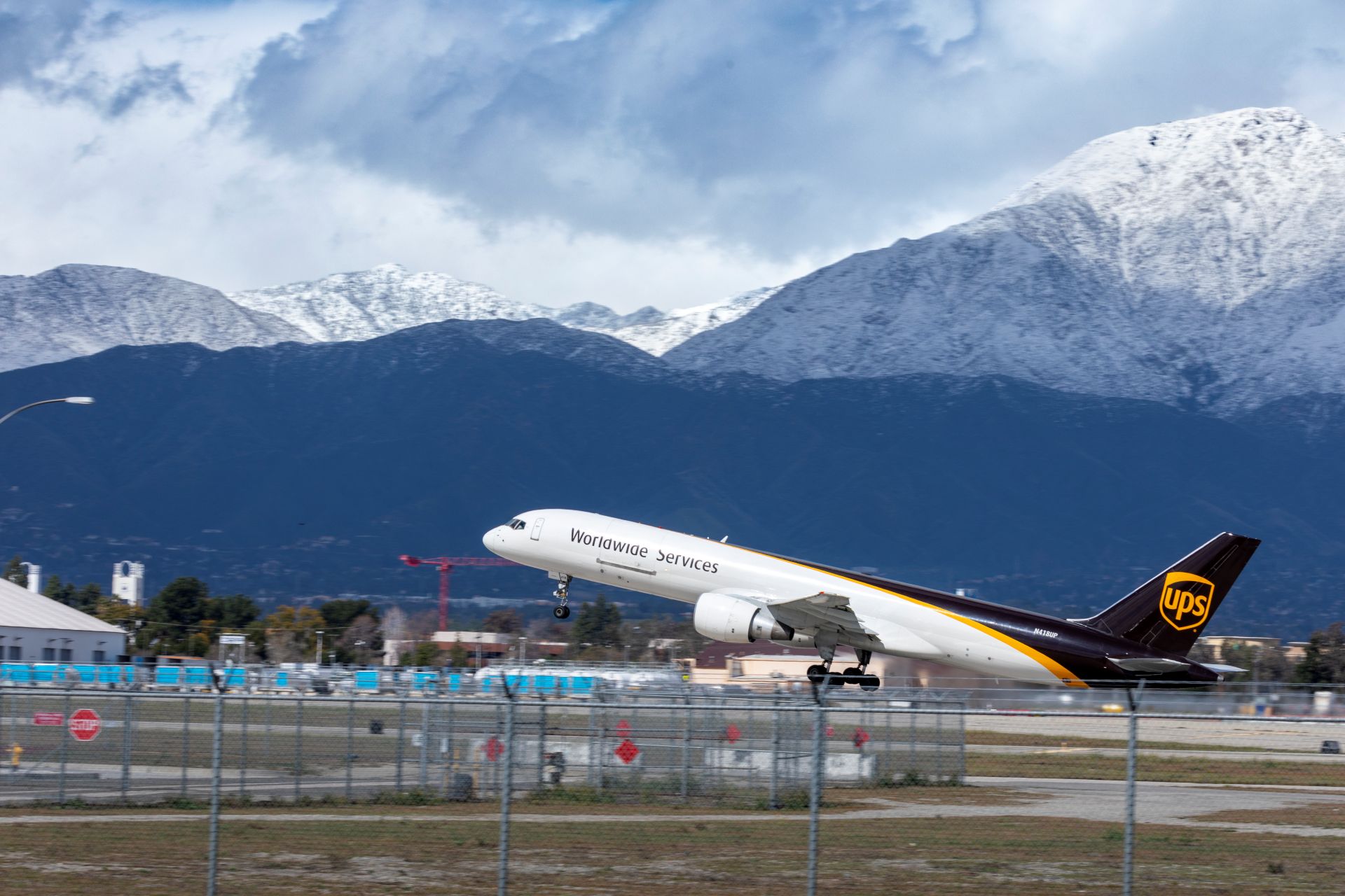 A UPS plane takes off from ONT with snowy mountains in the background.