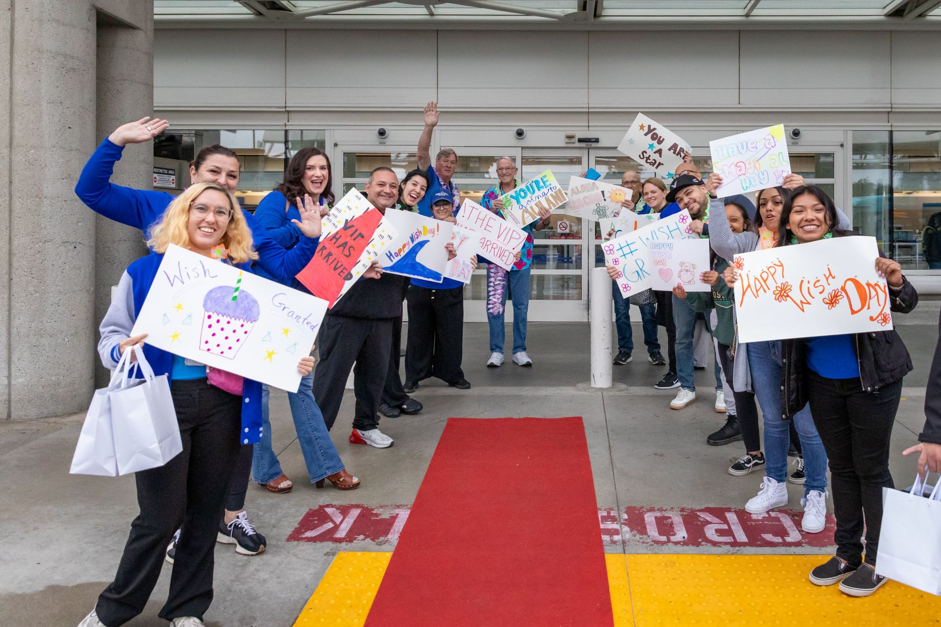 ONT staff members wave signs welcoming Make-A-Wish with a red carpet leading into ONT.