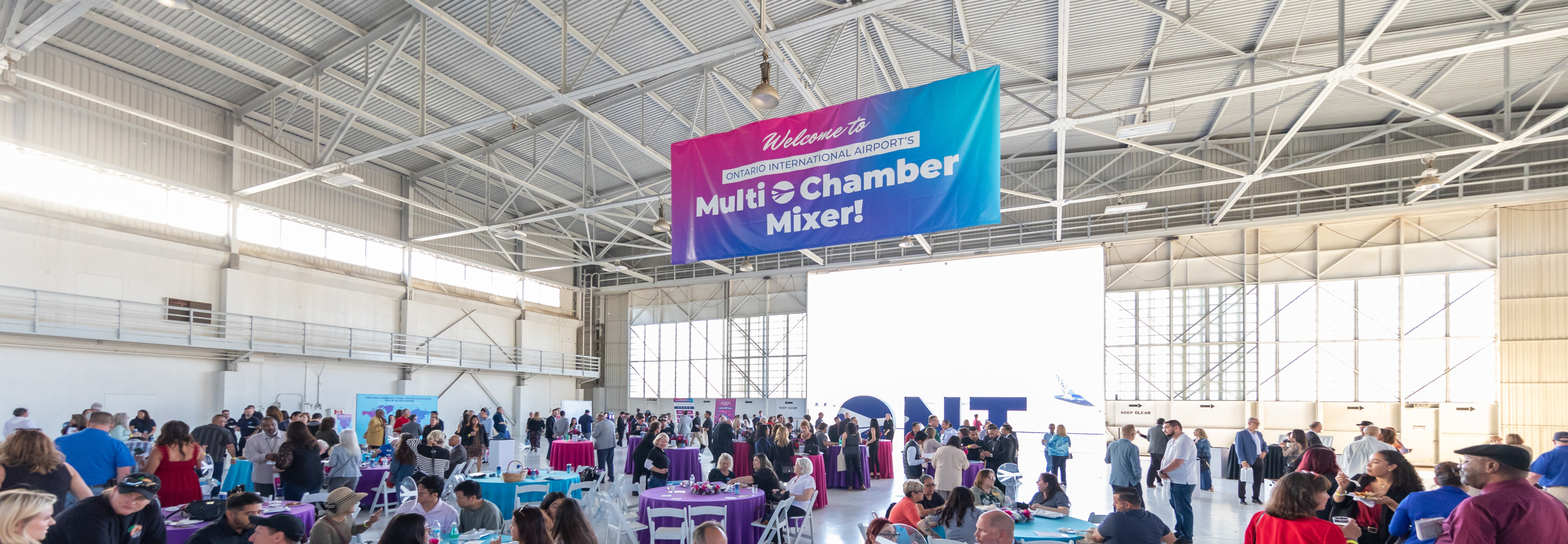 Bustling indoor convention center with rows of exhibition booths and displays.