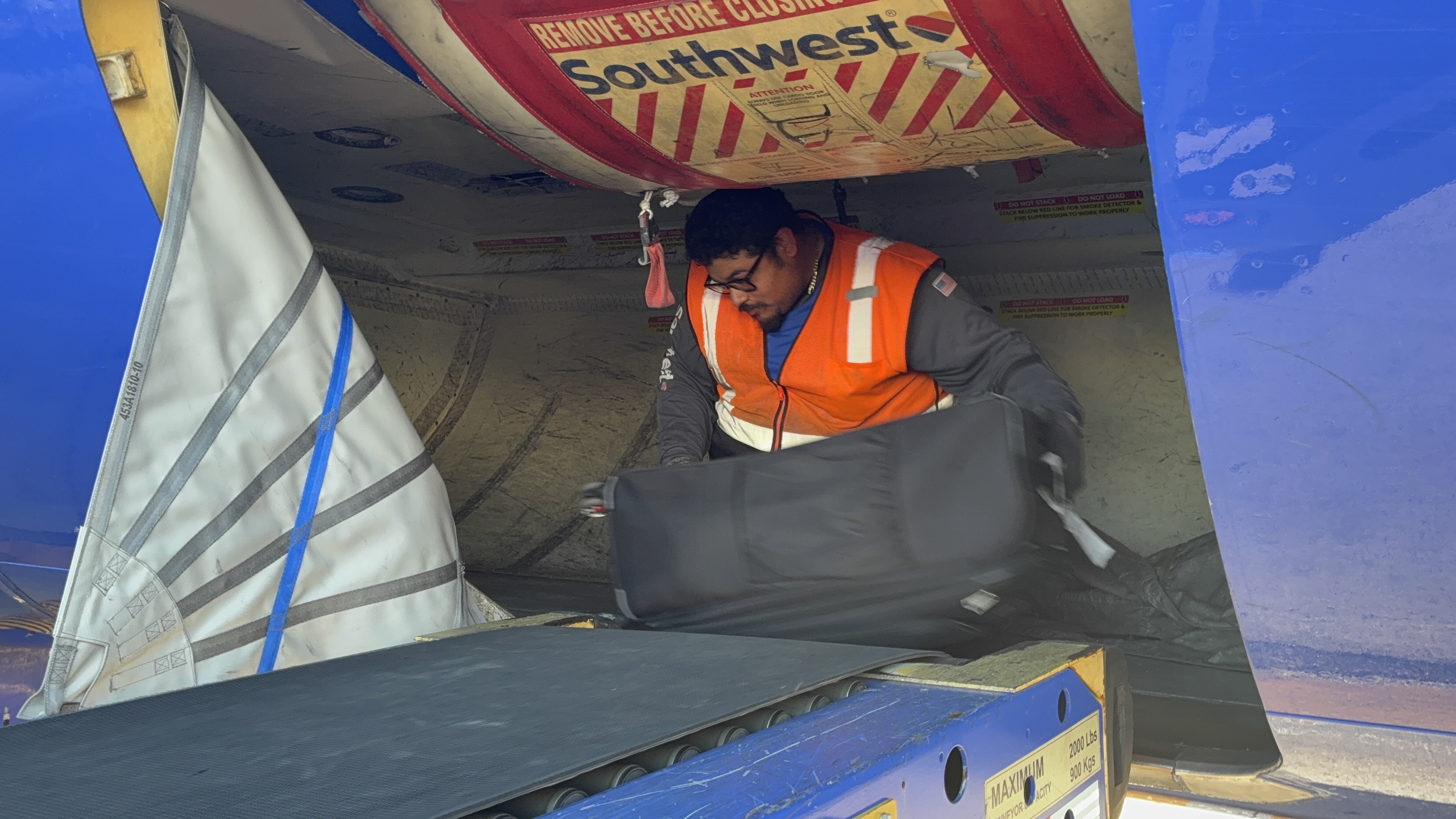 Baggage Handler inside bottom of plane organizing the luggage.