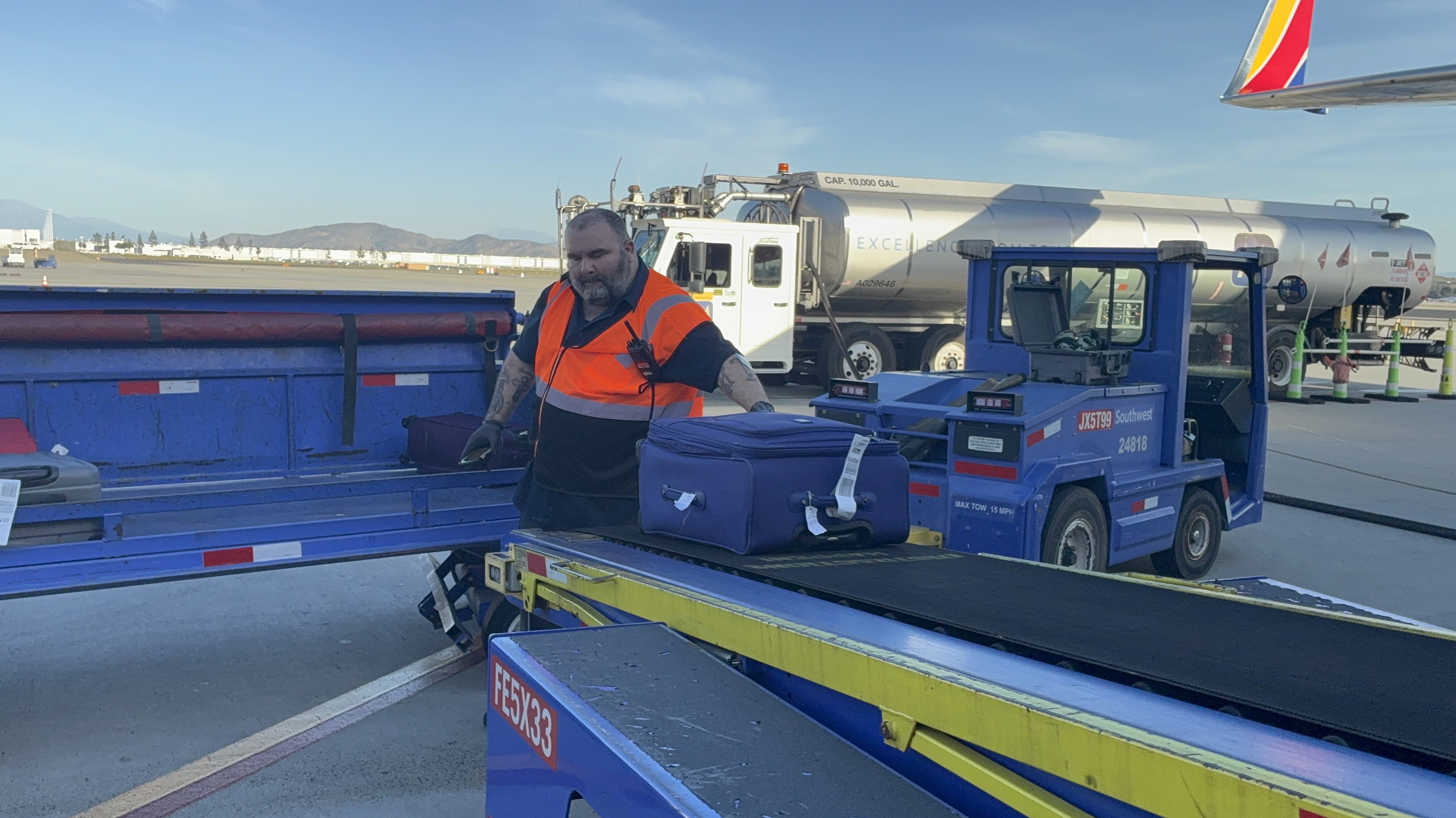 Baggage Handler Removing Luggage from Airplane Conveyor Belt