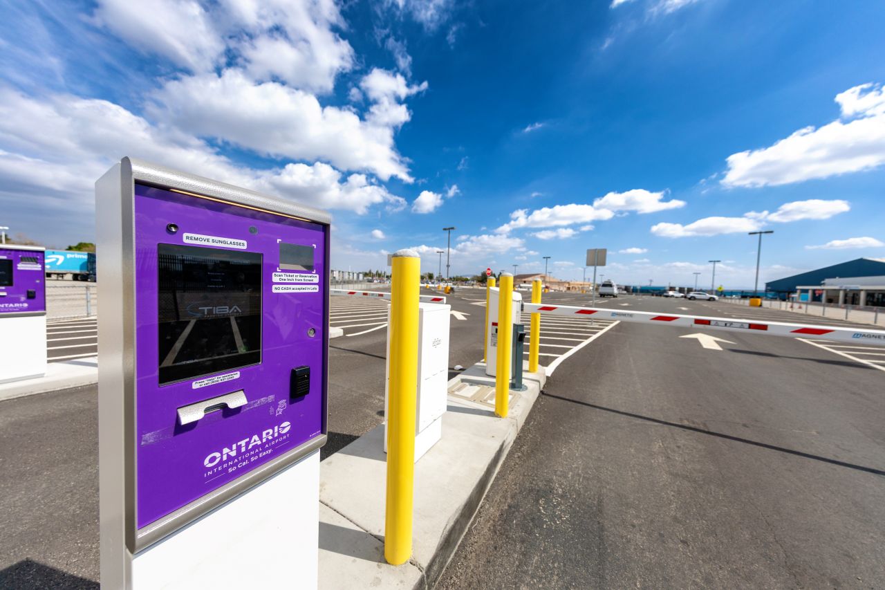 A purple parking machine sits at the parking lot entry with yellow safety pillars around it.