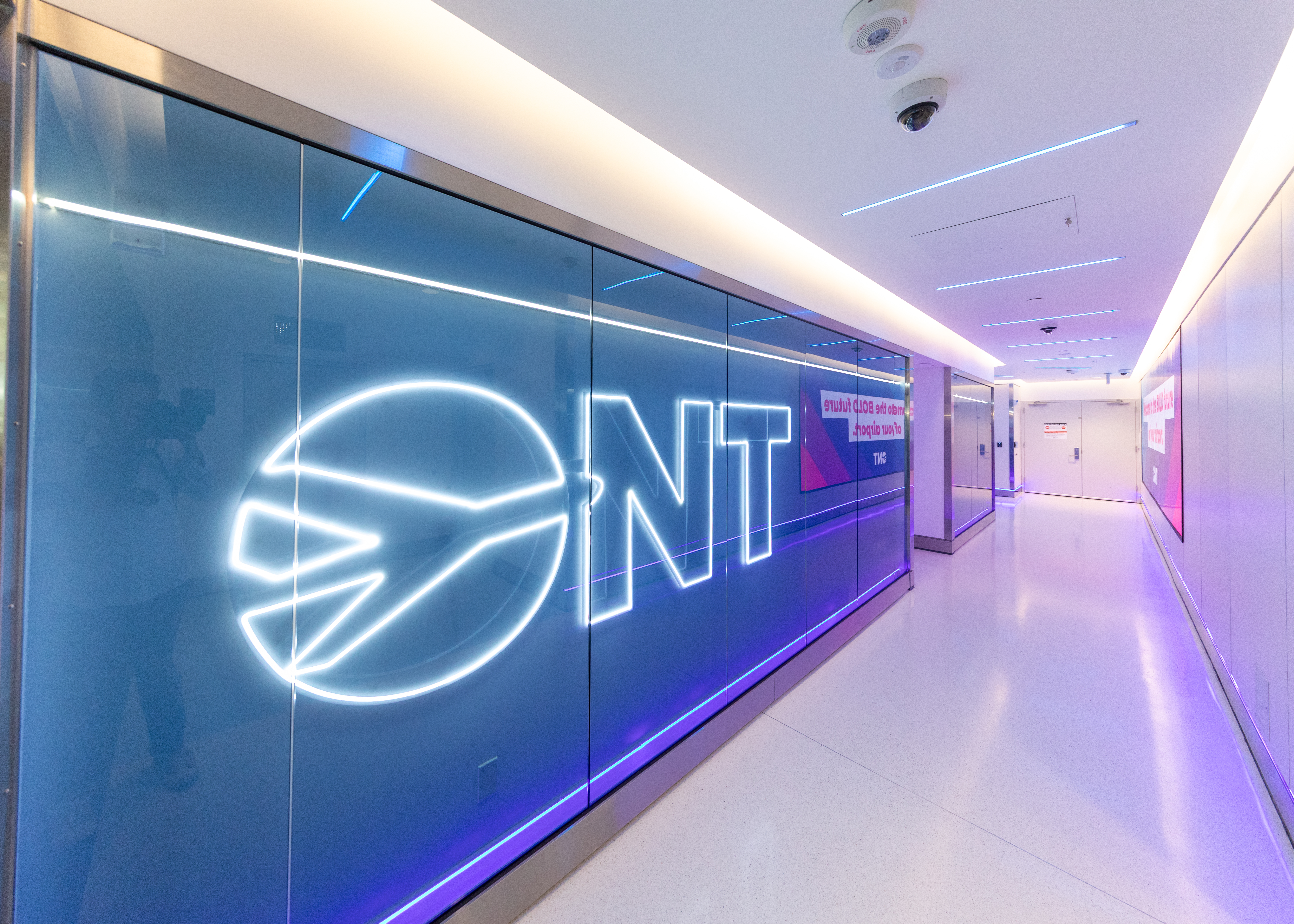 Modern hallway with blue wall featuring illuminated O N T logo and purple accent lighting