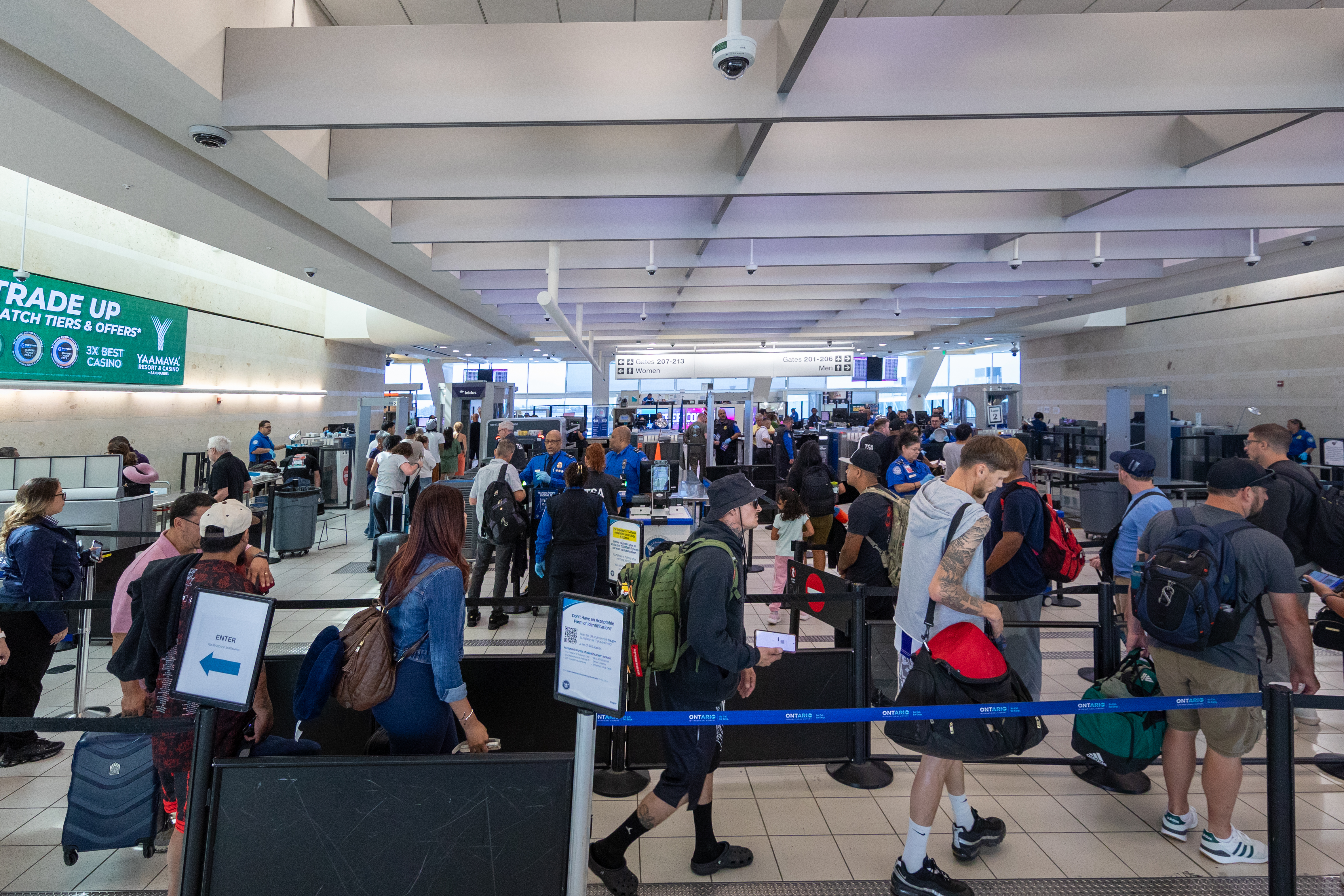 T S A area with queue of travelers at multiple counter desks