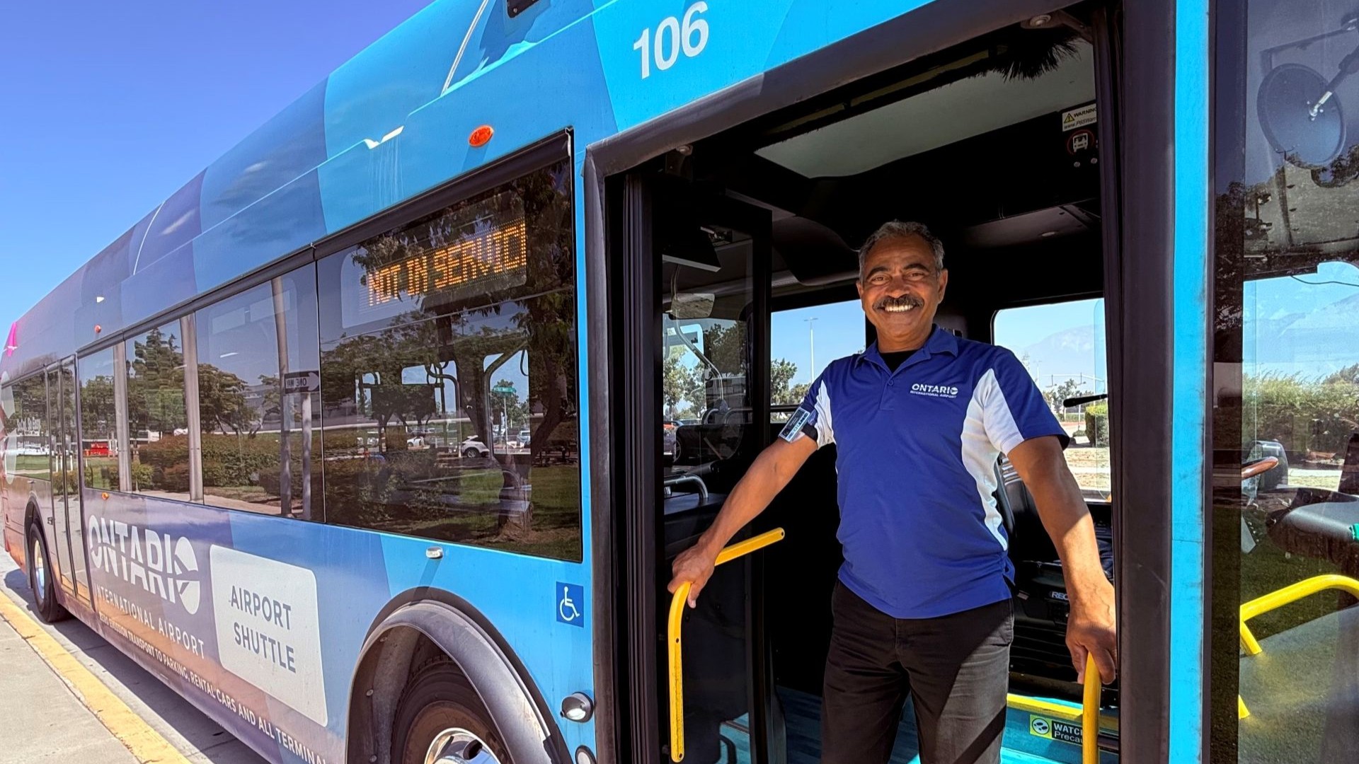 Michael, an ONT bus operator for the last five years, stands in front of his shuttle.