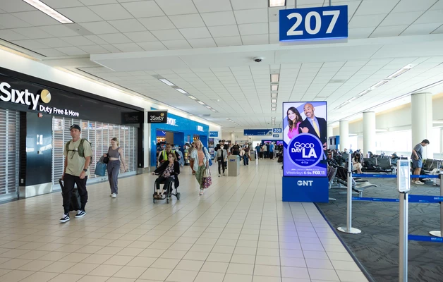 Airport terminal with travelers walking past gate 207 and retail shops
