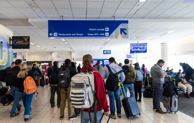 Crowded airport gate with passengers waiting to board, blue overhead signage