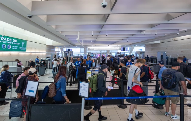 Busy terminal with winding line of passengers entering security checkpoint