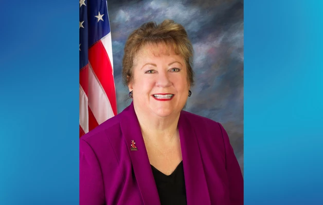 Commissioner Debra Porada smiling headshot with an American flag in the background.