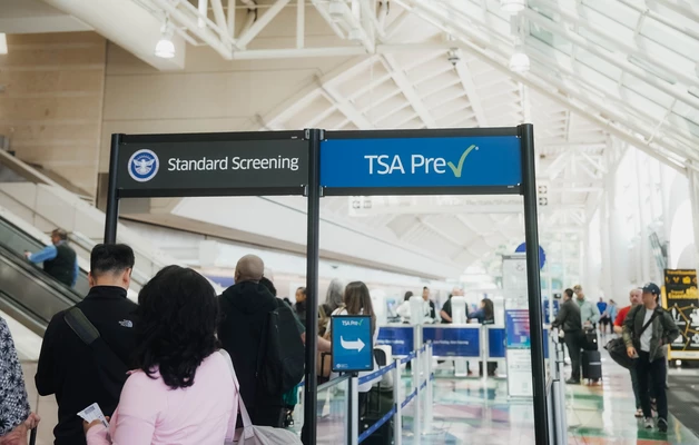Airport terminal with TSA PreCheck sign and passengers queuing at security checkpoint