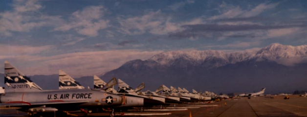 A line of U.S. Air Force planes is shown on the ONT runway in front of snow-capped San Gabriel Mountains.