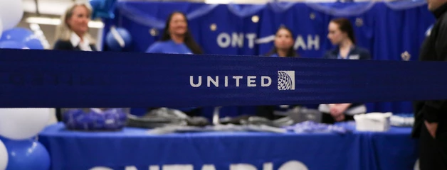 A blue belt that says "United" is show in front of an ONT table with staff working at the table.