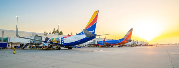 Southwest Airlines planes are shown at the gate with a sunset behind them.