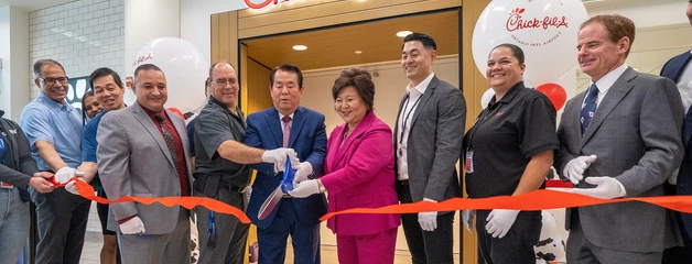 people cutting a ribbon to celebrate the opening of a new airport concessions