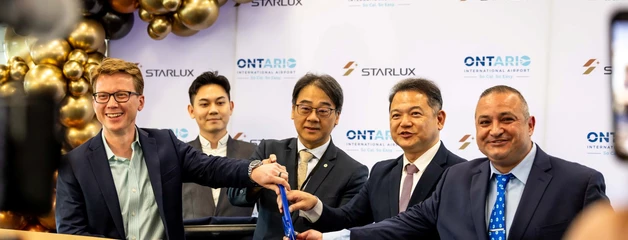 Five men use big scissors to cut a gold ribbon that says STARLUX.