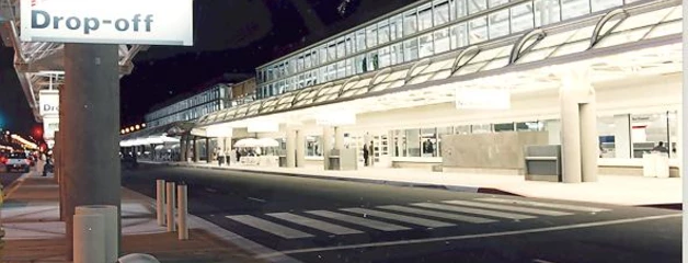 An empty drop-off area is shown outside the terminal at night.