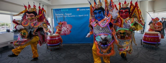 Brightly colored Chinese lion dancers perform in front of an audience in the terminal.