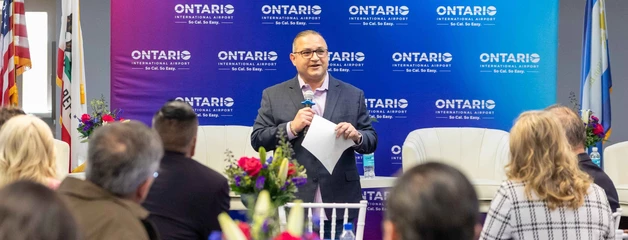 Ontario International Airport C E O speaking to a crowd and holding a microphone.