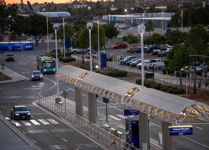 City intersection with multi-lane roads, transit station, and vehicles at dusk.